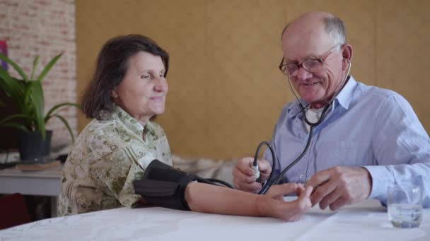 Zdravotní péče, pečující starší muž měří tlak své země s jeho milovanou manželkou krevní tlak pomocí — Stock video