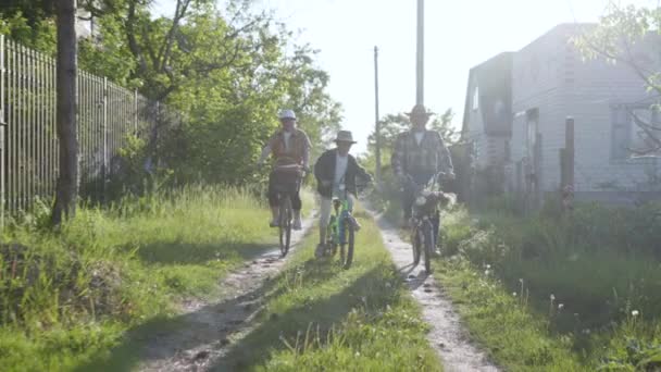 Estilo de vida, nieto feliz y sus felices abuelos se divierten y disfrutan de un paseo conjunto en bicicletas y montar en un camino rural — Vídeos de Stock