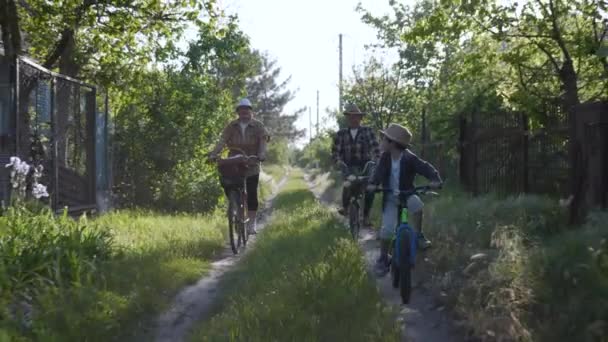 Dětství, šťastný bezstarostný muž dítě v slamáku klobouk s jeho milující prarodiče bavit jízdu na kole podél silnice mimo město mezi stromy na letních prázdnin — Stock video