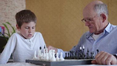 Mantıksal düşüncenin gelişimi, vizyon gözlüklü neşeli büyükbaba akıllı çocukla masa oyunları oynuyor.