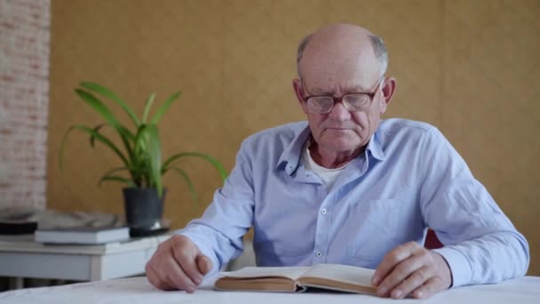 Soins pour les personnes âgées, homme âgé avec des lunettes pour la vue petit-fils aimant apporte de l'eau tout en lisant le livre — Video
