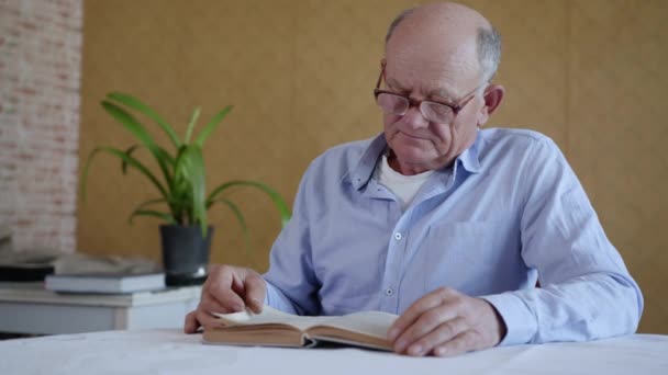 Cuidado de ancianos, un niño pequeño y lindo trae agua limpia y clara a su amado abuelo libro de lectura — Vídeo de stock