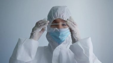 Yorgun kadın doktor, çok çalıştıktan sonra gözlüğünü ve maskesini çıkarır. Salgın ve karantina sırasında koronavirüs teşhisi konan hastaları tedavi eder.