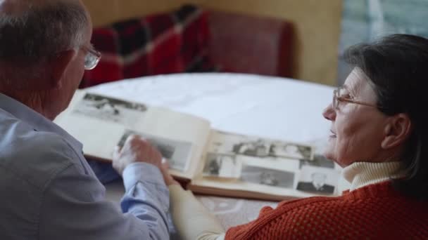 Relation amoureuse, tendre homme âgé avec sa vieille femme joyeuse jouit de souvenirs de famille tout en regardant des photos dans un album — Video