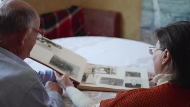Pohled shora, milující starší muž se svým úsměvem na manželku má rodinné vzpomínky při sledování fotografií v albu — Stock video