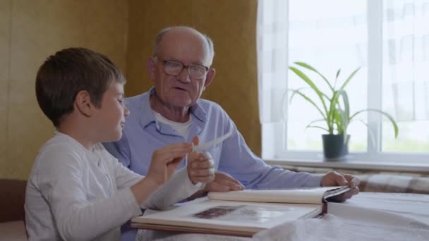 Beziehungsfamilie, freudiges männliches Kind, zusammen mit einem älteren Mann, wird Erinnerungen aus einem Fotoalbum erben — Stockvideo