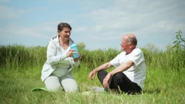 Yaşlı, sağlıklı bir çift sabah egzersizlerinden sonra spor yapıyor ya da yoga yapıyor ve temiz, serin su içiyor.