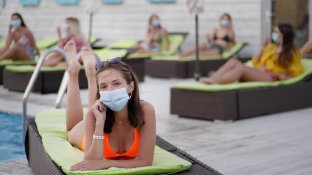 Pandemia, meninas em trajes de banho observar novas normas de distância social e tirar máscaras médicas protetoras do vírus e infecção — Vídeo de Stock