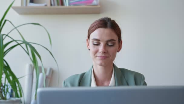 Bekijk van webcam, leraar kijkt naar camera zet vervolgens op bril terwijl zitten aan de tafel met een laptop in de klas — Stockvideo