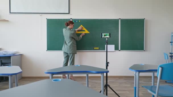 Leraar in de buurt van schoolbord met behulp van mobiele telefoon videocamera opnemen zichzelf op het leren van online wiskunde onderwijs op school tijdens zelfisolatie — Stockvideo