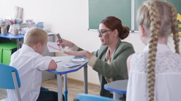 Menino com síndrome de downs responde a perguntas de professores sentados na mesa da escola durante a aula de matemática, escolaridade — Vídeo de Stock