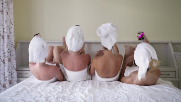 Νεαρά κορίτσια με όμορφο καλά καλλωπισμένο δέρμα σε πετσέτες να λάβει selfie στο smartphone, ενώ βρίσκεται στο κρεβάτι στο άνετο δωμάτιο — Αρχείο Βίντεο