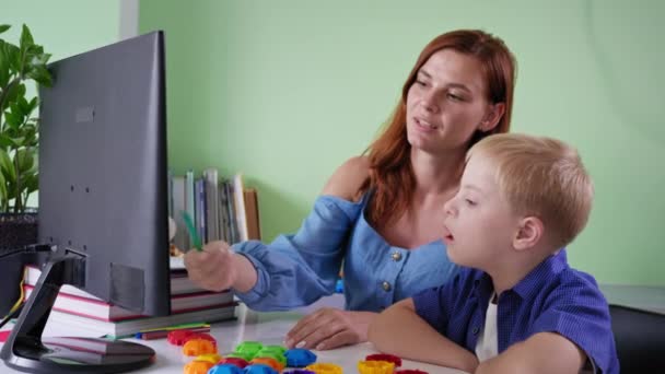 Istruzione a distanza per bambini, scolaro con sindrome di Down studi con pedagogia femminile durante la lezione a casa seduto al computer in camera — Video Stock