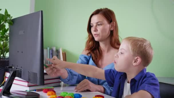 Aluno em casa, estudante com síndrome de down fazendo lição de casa com a professora usando o computador na sala durante a pandemia — Vídeo de Stock