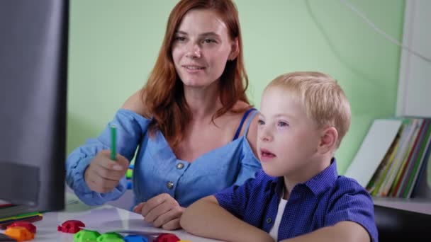 Em casa, menino bonito com síndrome de down aprender lições com a mãe, em seguida, dá cinco para os pais sentados no computador no quarto — Vídeo de Stock