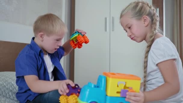 Famiglia tempo, sorella e ragazzo con la sindrome di Down divertirsi con auto giocattolo colorate sul letto a casa — Video Stock