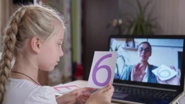 Çevrimiçi öğrenme, dizüstü bilgisayarda oturan ve Coronavirus 'taki kadın öğretmenini dinleyen kız.