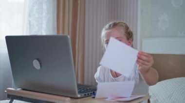 Evde eğitim gören çocuk, öğrenci kız koronavirüs zamanında dizüstü bilgisayarla otururken öğretmenle internet üzerinden iletişim kurmayı öğreniyor.