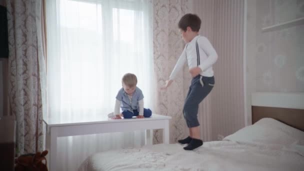 Les enfants s'amusent à la maison, les frères heureux sautent sur le lit au ralenti — Video
