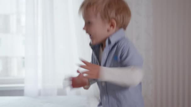 Criança ativa em casa, feliz engraçado menino pulando diversão na cama e palmas — Vídeo de Stock