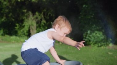 Çocukluğun tadını çıkar, küçük çocuk yaz parkında sprey şişeden su dökülüyor. Kapatın.