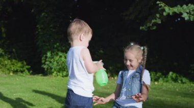 Çocuklar suyla oynar, erkekler yaz tatili boyunca kızların arka planlarına sprey sıkarlar.