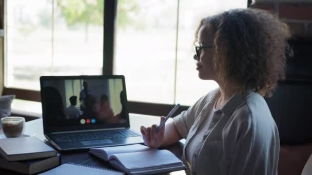 Modern utbildning, kvinnlig student genomgår online-utbildning höjer handen och gör anteckningar i anteckningsboken medan du sitter med bärbar dator vid bordet i wifi café — Stockvideo