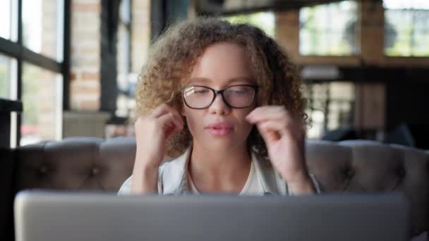 Flicka tar av glasögon för syn och tittar ut genom fönstret när du arbetar på laptop — Stockvideo