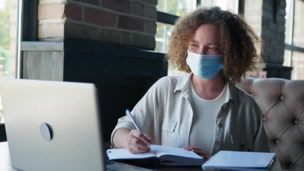 Dziewczyna w masce medycznej pracuje z komputerem w restauracji — Wideo stockowe