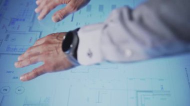 In an office, leaning over a large monitor instead of a desk, a man actively uses an interactive diagram on the screen. He then minimizes and removes the drawing file from the monitor screen. The