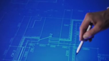 In an office, leaning over a large monitor instead of a desk, a man actively uses an interactive diagram on the screen. The camera focuses on his hand with a stylus, actively interacting with an