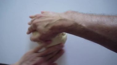 Men hands in the kitchen on a white kitchen table knead a piece of dough, turning it as if it were a steering wheel. Top view from the first person on man hands. Big close up shot