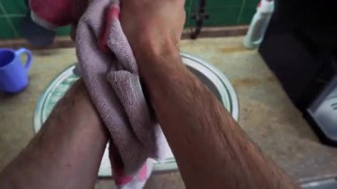 In the kitchen, after washing dishes, a man wipes his strong hands with a towel. Top view from the first person. Big close up shot