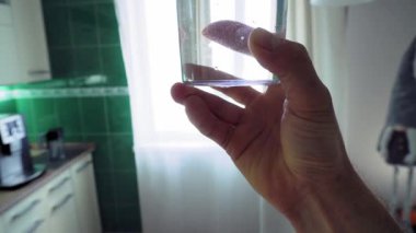 In the kitchen, a man is preparing dough by adding the necessary ingredients to a glass bowl of flour. Everything needed for the cooking process is neatly arranged on the kitchen table. Before adding