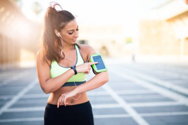 cep telefonu kullaranarak earphones ile Bayan açık havada dinleme müzik spor