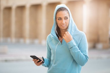 cep telefonu kullaranarak earphones ile Bayan açık havada dinleme müzik spor