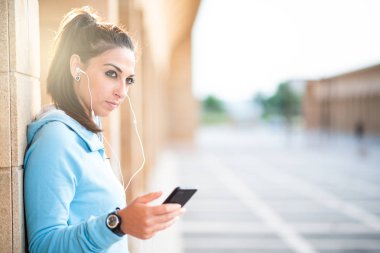 cep telefonu kullaranarak earphones ile Bayan açık havada dinleme müzik spor