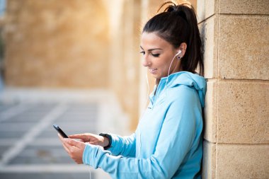 cep telefonu kullaranarak earphones ile Bayan açık havada dinleme müzik spor