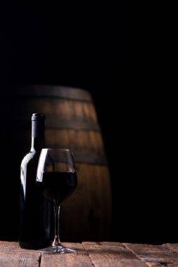 Bir şişe opf kırmızı şarap ve arka plan üzerinde varil ile bir bardak