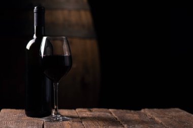 Bir şişe opf kırmızı şarap ve arka plan üzerinde varil ile bir bardak