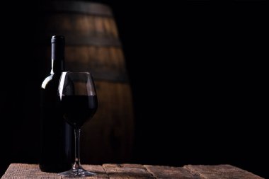 A bottle opf red wine and a glass with barrel on background clipart