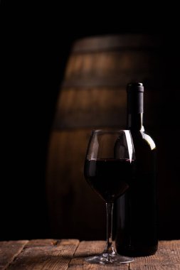 Bir şişe opf kırmızı şarap ve arka plan üzerinde varil ile bir bardak