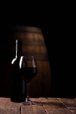 Bir şişe opf kırmızı şarap ve arka plan üzerinde varil ile bir bardak