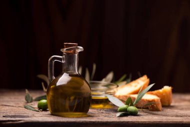 Ahşap bir masa üzerinde ekmek ile zeytinyağı. Rustik vintage kompozisyon