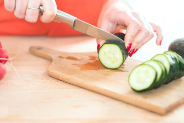 kadın mutfakta kesme tahtası üzerinde bıçak ile kesme taze sebze eller