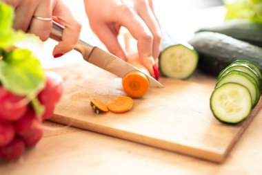 kadın mutfakta kesme tahtası üzerinde bıçak ile kesme taze sebze eller