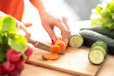 kadın mutfakta kesme tahtası üzerinde bıçak ile kesme taze sebze eller