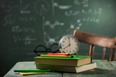 8: 00 okul kavramı ile geri. Yazı tahtası üzerinde arka plan ile çalar saat kitapları