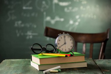 8: 00 okul kavramı ile geri. Yazı tahtası üzerinde arka plan ile çalar saat kitapları
