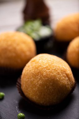 Arancini pilav et topu tabak tabak taze bezelye ve rustik masada fesleğen ile hizmet veren siyah yakın çekim.